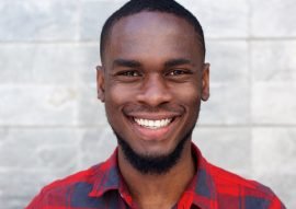 happy-young-african-man-smiling-against-gray-wall-PSC64N4.jpg